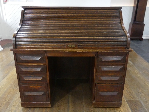 An early 20thC American oak roll top Desk, marked 'Cutler', the serpentine tambour front revealing