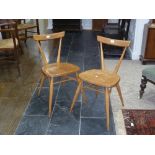 A pair of mid 20thC light elm and beech Ercol Stacking Chairs, both with holographic sticker labels,