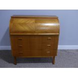 A mid 20thC teak roll top Bureau, the quarter veneered roll top revealing a fitted interior, three