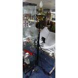 A vintage brass Aladdin Model 12 lamp, stood on later wrought iron stand, 65in (165cm) tall.