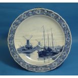 A large Dutch Delft Charger, with gadroon shaped edges, hand painted in blue tones with a scene of