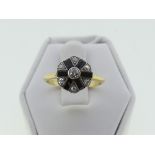 An Art Deco diamond and black onyx Cluster Ring, the central diamond surrounded by six smaller,