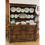 A late 19thC oak Dresser, the carved top rail with scroll ends above the slat back with two shelves,