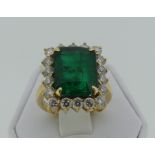 A large emerald and diamond Dress Ring, the central emerald cut stone circa 7cts (39mm x 6.6mm)
