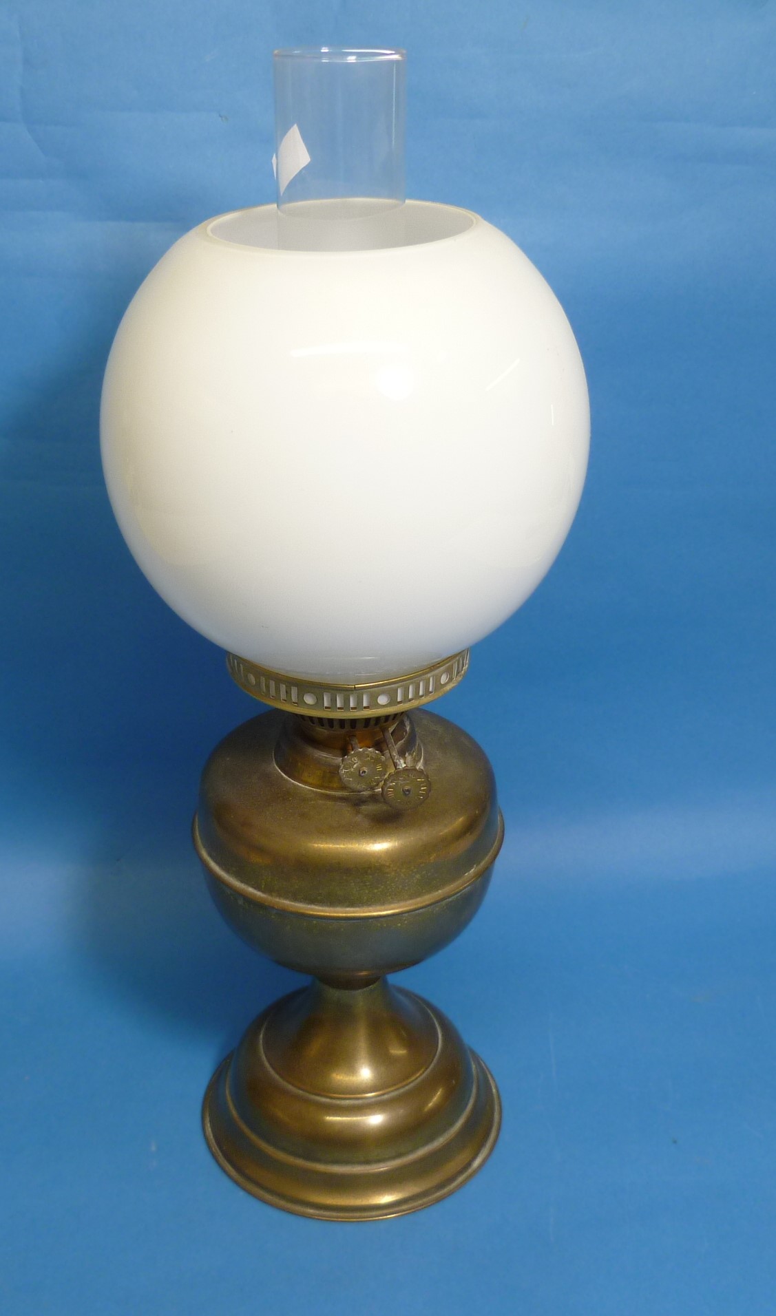 A Victorian brass Oil Lamp, with white glass globe and clear funnel, 19½in (49.5cm) high.