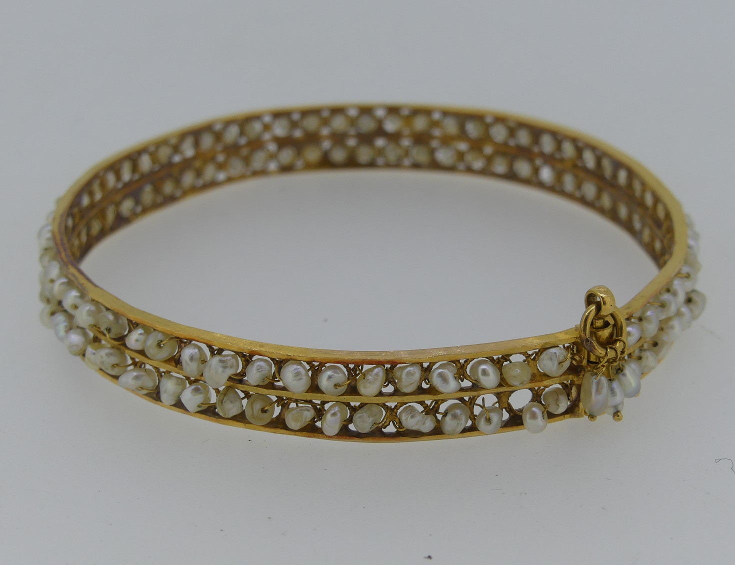 A hinged Bangle, formed of four rows of cultured pearls within a ropework frame, unmarked but tested - Image 2 of 2