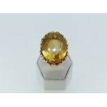 A very large citrine Dress Ring, the oval facetted stone in a gold cagework mount and shank, all