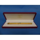 A 'Must de Cartier' gold plated ball point Pen, with a textured finish, in leather presentation