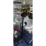 A vintage brass Aladdin Model 12 lamp, stood on later wrought iron stand, 65in (165cm) tall.