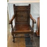 A 18th century Armchair, the solid foliate carved back above a board seat, scroll arms with turned