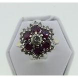 An 18ct white gold, ruby and diamond Cluster Dress Ring, of hexagonal form, the central diamond c.