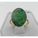 An oval Jade Ring, the oval jade pierced and carved with leaves, in unmarked yellow gold, tested