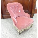 A Victorian child's button-back armchair, upholstered in pink velour, on turned legs with brass caps