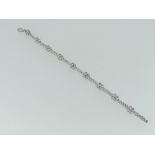 A 18ct white gold Bracelet, set with alternate clusters of four and rows of three white pastes,