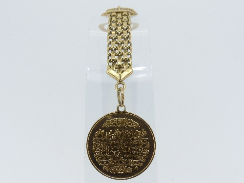 An Eastern gold Key Ring, marked on the clasp 750, suspending a circular medallion with Arabic