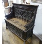 A late Victorian carved oak box seat Settle, with stylized foliate carvings and animal mask arm