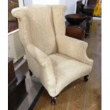 An early 20thC Georgian style Wingback Arm Chair, upholstered in figured dark cream fabric, raised