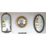 A gilt and black framed oval Wall Mirror, with bevelled glass, 27½in (70cm) long, together with a