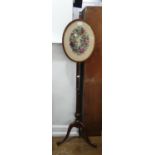 A Victorian mahogany Pole Screen, the adjustable oval panel with foliate needlework centre, 55in (