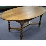 An Edwardian oak oval Dining Table, the planked top, raised on barley-twist supports and Y-