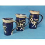 A set of three Graduated Jugs by Sally Seymour, of navy blue ground, with cow decoration and gilt