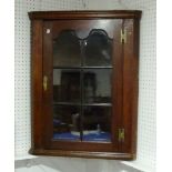 A Georgian oak hanging Corner Cabinet, the moulded cornice above panelled glazed doors enclosing