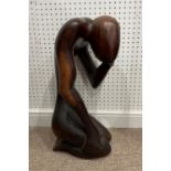 A 20thC African hardwood Carving, of a stylized figure, kneeling with head in hand, 66cm high.