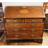 A George III mahogany Bureau, the fall front with central inlays, enclosing fitted interior upon two