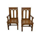 A PAIR OF EARLY 20TH CENTURY ECCLESIASTICAL OAK ARMCHAIRS