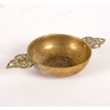 A small brass porringer with pierced foliate handles and central rose motif,