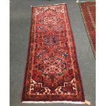 A Heriz rug, the red ground with three medallions to a geometric border,