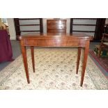 A George III style mahogany card table of serpentine form on square tapering legs,