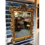 An 18th Century style gilt framed mirror, the pierced, scrolling frame fitted a bevelled glass,