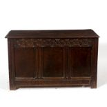 A late 18th Century oak chest with carved frieze, planked top and wrought iron hinges,