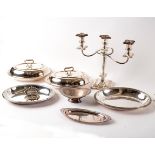 A silver plated three-branch candelabra, a pair of plated entree dishes, another entree dish,