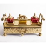 An engraved brass inkstand and pen tray, circa 1930, with Rococo style handles, fitted ink pots,
