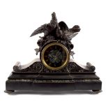 A black slate mounted clock with bird surmount,