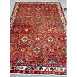 A Hamadan rug with claret ground, the all over geometric field within a multiple border,