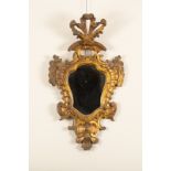 An Italian giltwood wall mirror of Baroque design, with pierced surmount and scroll surround,