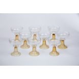 A set of nine champagne coupes with clear glass bowls on spiralling amber feet