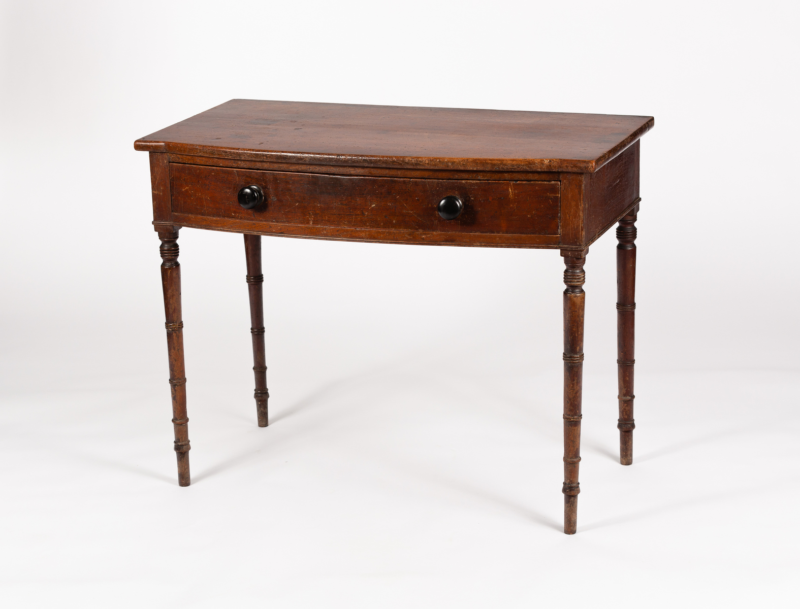 A George IV bowfront side table fitted a drawer, on turned legs,