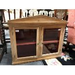 A hanging pine cupboard enclosed by a pair of glazed doors,