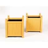 A pair of ochre painted wooden square planters with ball finials and slatted sides,