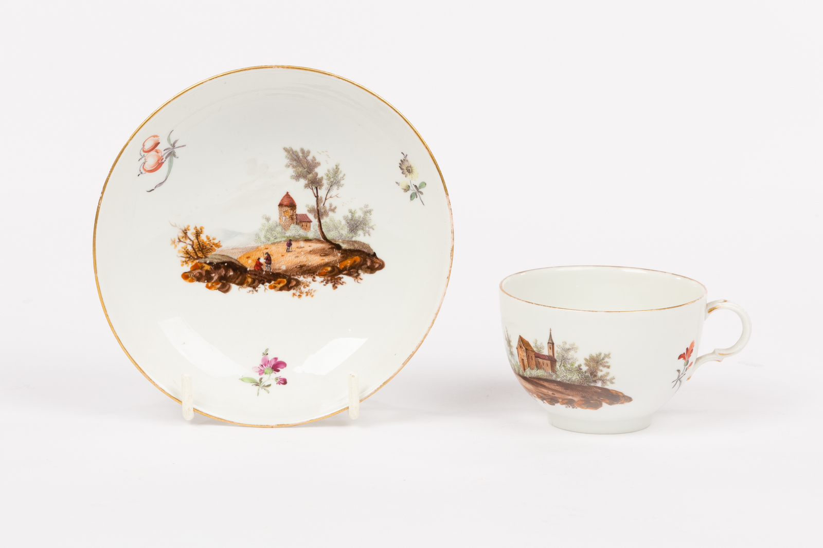 A Furstenberg teacup and saucer, late 18th Century, painted landscapes and scattered sprigs,