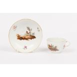 A Furstenberg teacup and saucer, late 18th Century, painted landscapes and scattered sprigs,