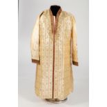 An Indian cream silk coat with gold and claret embroidery embellished with red glass stones and