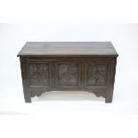 A 17th Century oak chest, the hinged cover above a carved triple-panel front,