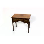 An early 19th Century oak kneehole table fitted a surround of three drawers with shaped apron,