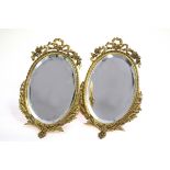 A pair of gilt metal framed oval mirrors, with easel backs,