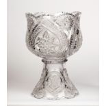 A large cut glass punch bowl with serrated border with cut stars and cosmic leaf shaped reserves,